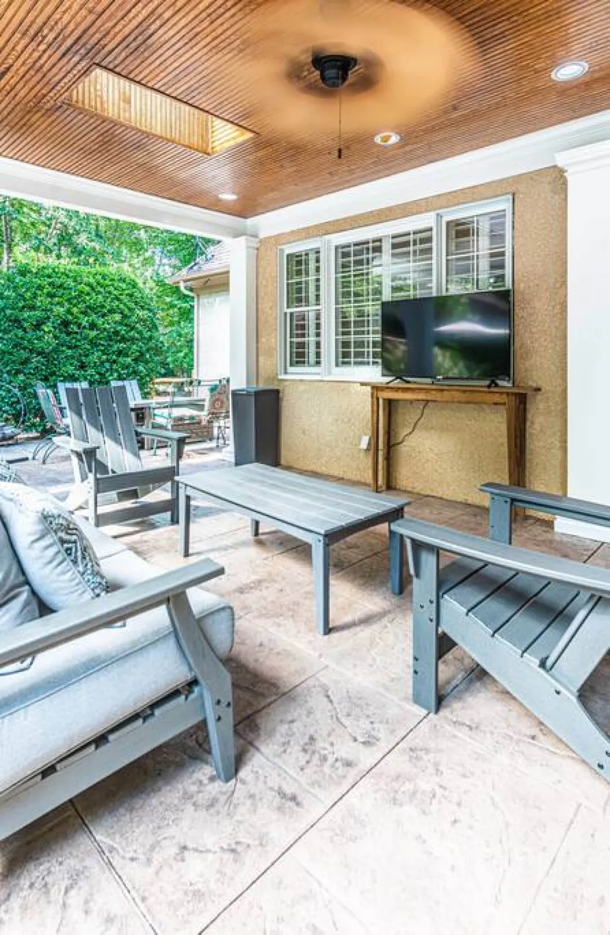 A comfortable living space with plush seating facing a large TV, bathed in natural light from generous windows. The relaxed arrangement invites guests to unwind, socialize, or enjoy entertainment via the smart TV.