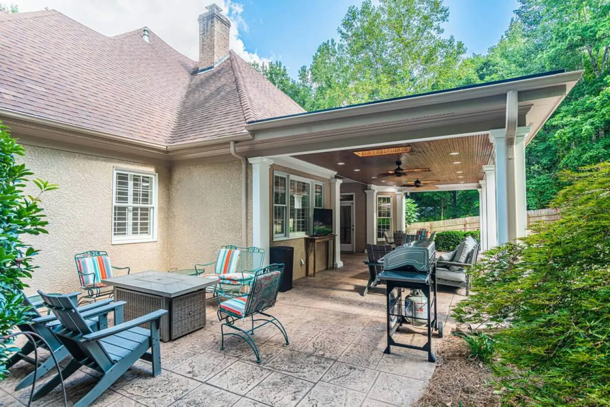 An inviting outdoor seating area on a covered patio, featuring a modern grill and comfortable lounge chairs. The space is styled for relaxation and group gatherings, with open sightlines to the surrounding yard and plenty of room for team members to spread out and socialize.